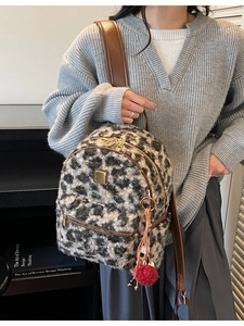 Fashionable leopard faux fur backpack with leather straps and a red pompom keychain