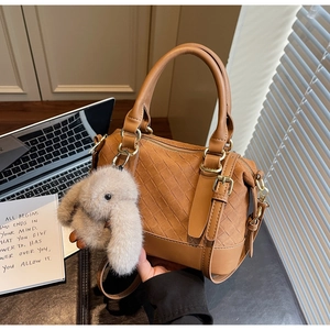 Detailansicht der braun gewebten Boston-Tasche aus PU-Leder mit Plüschkaninchen-Anhänger