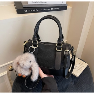 Detail der schwarzen geflochtenen Handtasche mit Hasenanhänger und goldenen Beschlägen