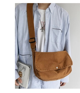 Brown canvas messenger bag detail with silver buckle worn by a model in casual outfit
