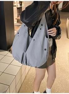 Detail of gray nylon tote bag with metal eyelets and waterproof texture on female model