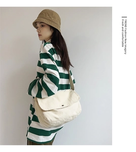 Detail view of cream canvas messenger bag with wide strap and minimalist flap design