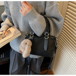 Detail of black woven leather baguette bag with plush rabbit charm and silver hardware