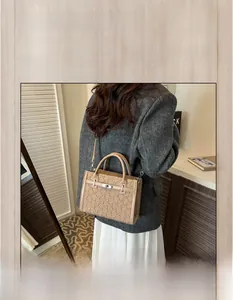 Detail of a beige pleated Kelly style handbag showing textured surface and shoulder strap