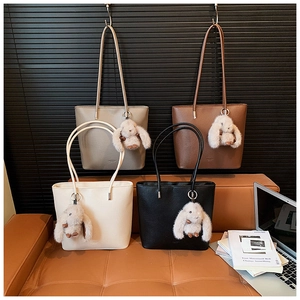 Detail view of four large capacity tote bags in neutral colors with plush bunny charms