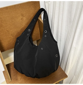 Detail of black nylon tote bag with silver metal eyelets on a wooden chair