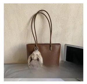 Brown lychee-textured leather bucket bag with cute grey rabbit plush charm and long straps