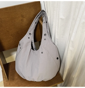 Detailed macro of grey wrinkled nylon tote bag with black metal eyelets on a wooden chair