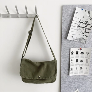 Detail of army green canvas crossbody bag with silver buckle and adjustable black strap