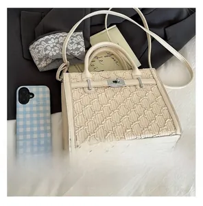 Detail of cream quilted handbag with metal twist lock and textured stitch pattern