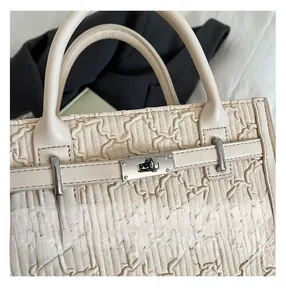 Detail of off-white quilted leather handbag showing metallic twist lock and fine stitching