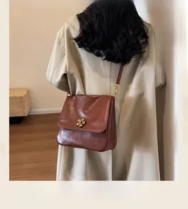 Detail view of a vintage brown leather crossbody bag with a floral gold metal buckle