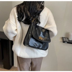 Detail of glossy black PU leather bag with vintage golden flower lock on shoulder