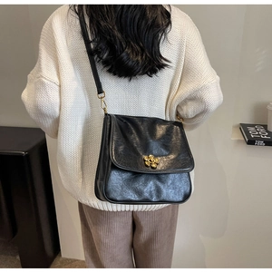 Detailed view of black vintage leather crossbody bag with a gold flower buckle accent