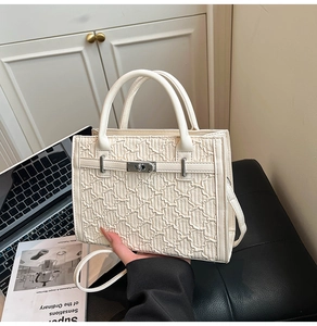 Detail of white quilted texture and silver twist lock on this stylish crossbody bag