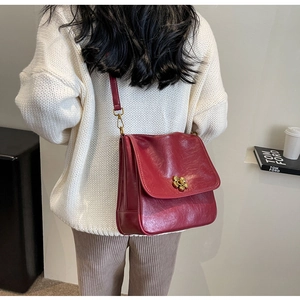 Detail of burgundy leather shoulder bag featuring a vintage golden floral buckle closure
