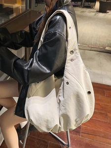 Minimalist off-white large nylon tote bag with metal eyelets worn by a model in casual style