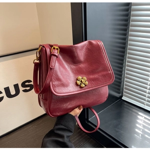 Close-up of wine red faux leather bag featuring a gold flower-shaped rotating lock buckle
