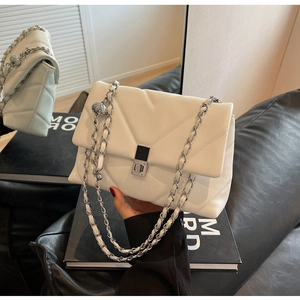 Detailansicht der weißen gesteppten Ledertasche mit silbernem Drehverschluss und Kette