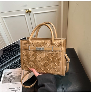 Detail of tan Kelly style bag with geometric embossed texture and silver twist lock closure