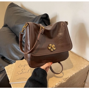 Detailed shot of retro brown leather handbag with gold floral clasp and adjustable strap