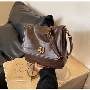 Macro detail of dark brown oil wax leather bag featuring a vintage gold floral metal buckle