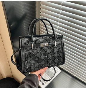 Detail of black faux leather handbag with geometric embossing and silver metal lock