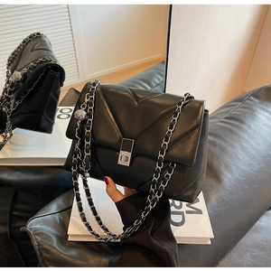 Nahaufnahme der schwarzen V-gesteppten Ledertasche mit silbernem Drehverschluss und Kette