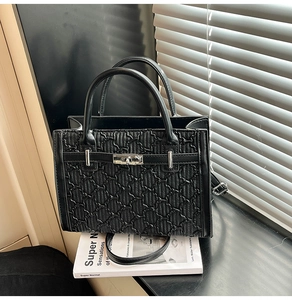 Detail of black tote bag with star embossing, silver twist lock and leather shoulder strap