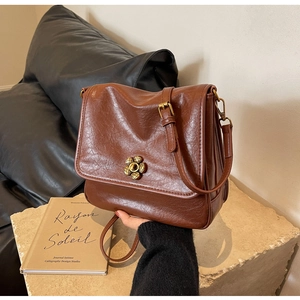 Detailed macro of vintage caramel brown leather bag texture and metal flower buckle
