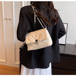 Detail der cremeweißen Stepptasche mit V-Nähten und silberner Metallkette für Damen