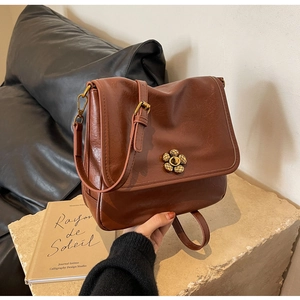 Close-up of brown textured leather handbag featuring a golden flower metal clasp
