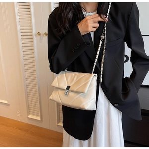 Schicke gesteppte beige Kettentasche an einem Modell mit eleganten silbernen Metallteilen