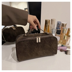 Détail de la trousse de toilette marron mat avec double fermeture éclair et poignée