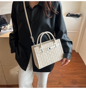 Detail of cream crossbody bag featuring vintage embossed texture and metallic turn-lock