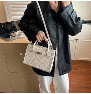 Detailed view of white textured handbag with silver twist lock and stylish wave pattern