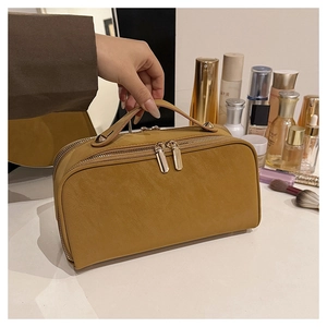 Détail d'une trousse de toilette jaune gingembre, texture cuir et double fermeture