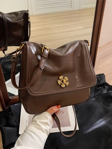 Retro brown crossbody bag with gold floral clasp shown in a mirror reflection