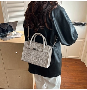 Detail view of beige Kelly style handbag with embossed bear pattern and metal buckle