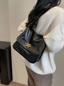 Classic black shoulder bag with gold floral clasp shown from a stylish side view angle