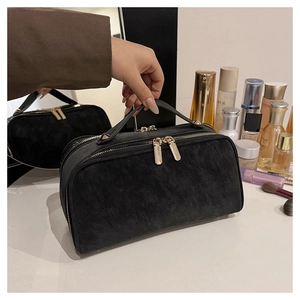 Détail de la trousse de toilette noire mate avec fermetures dorées et poignée élégante