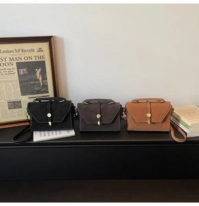 Three vintage matte crossbody bags in black, dark coffee and caramel displayed on books