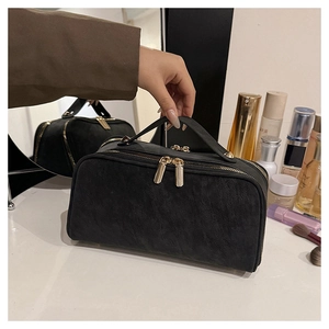 Détail d'une grande trousse de toilette noire avec doubles fermetures dorées de luxe