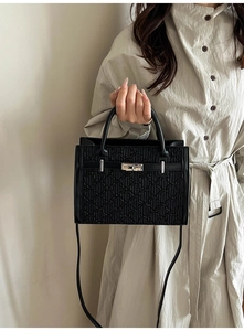Detail of black crossbody bag with bear-pattern quilting and silver metal twist lock