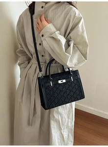Model wearing a black textured leather bag with silver buckle and detachable shoulder strap