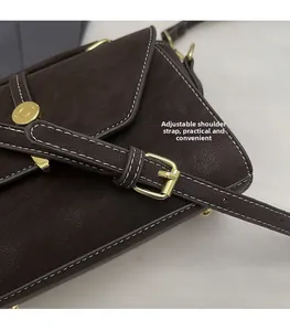 Detail of adjustable shoulder strap and gold buckle on a brown vintage leather bag