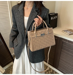 Detail of wave-textured khaki handbag with silver lock shown in a lifestyle setting