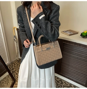 Detail of beige quilted handbag featuring a metallic twist-lock closure and shoulder strap
