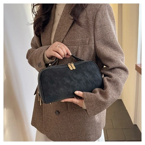 Détail de la trousse de toilette noire mate avec doubles zips dorés par un mannequin