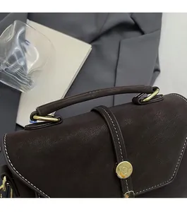 Detailed macro view of the dark brown leather handbag handle and gold metal hardware